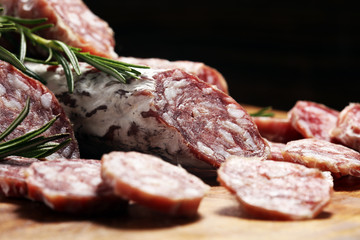 thinly sliced salami sausages on a wooden texture on the background.