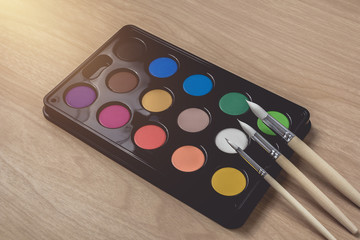 Paintbrush and Watercolor palette on brown wood table.using for Arts and Education background