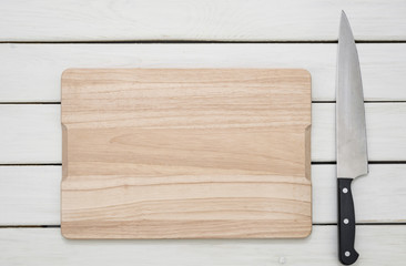 Rustic culinary template - top view of an empty cutting board and knife on a white wooden table.