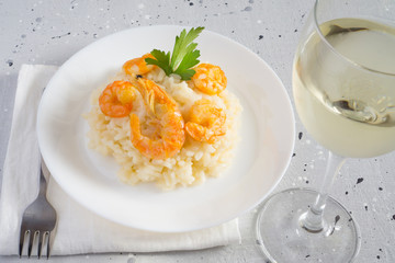 Risotto with shrimps and parsley on a white plate on a light gray background with copy space. Italian food