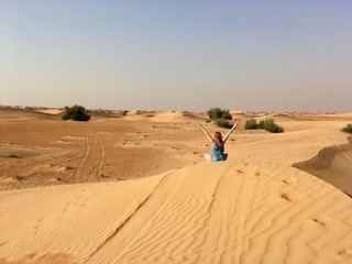 Fototapeta na wymiar Girl on top of a dune in the desert