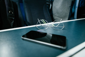 Focus on titanium eyewear glasses with new modern smartphone on train table inside British train 