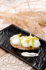 Delicious poached egg sandwich and bell pepper slices on rye toast on a black square plate. Beautiful light composition with yellow ears in the background. Close up. Space