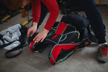 Woman rigger is packing parashute before jumping in the aerodrome room close-up. Face is not...