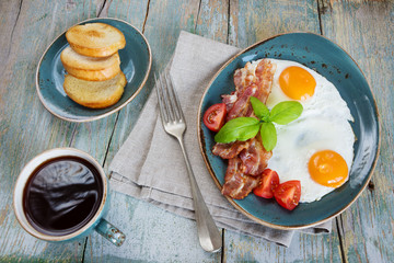 Fried eggs,  bacon, tomato, toast and a cup of coffee