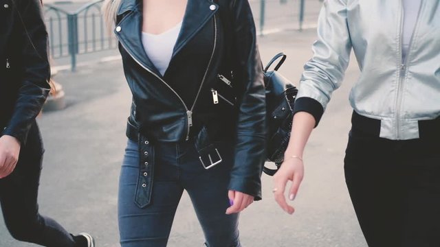 Trendy casual look. Ladies in jeans, moto and bomber jackets walking confidently down the city street.