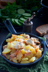 Fried potatoes with chicken on a cast-iron pan, selective focus