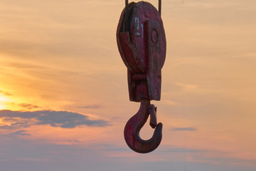 Hook from the lifting mechanism on the background of the sunset sky. crane hook