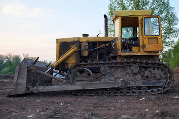 Yellow tracked tractor with lowered shovel