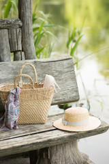 Thatch straw hat with bag basket on a wooden bench in summer women accessories