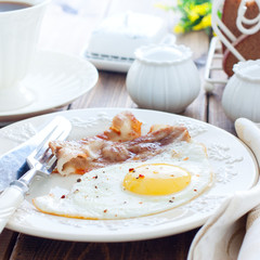 Breakfast of bacon and eggs on a wooden table, square