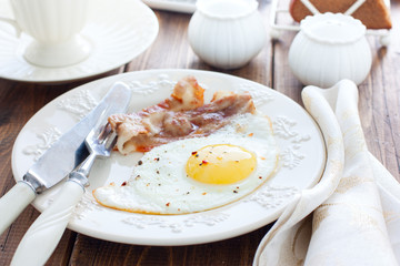 Traditional English breakfast of fried eggs with bacon on a wooden table, horizontal