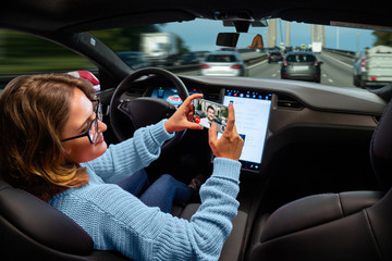 Woman communicates by video call while her car is driven by an autopilot. Self driving and...