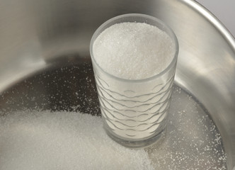 Glass of granulated sugar in a saucepan, cooking dessert