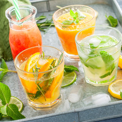 Assorted summer cold citrus drinks on a metal tray, square