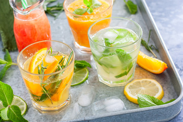 Assorted summer cold citrus drinks on a metal tray, horizontal