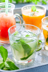 Mojito on the background of summer cold drinks with citrus fruits: lemonade, oranzhad, grape juice and mandarin juice, selective focus