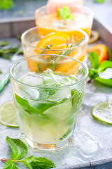 Mojito on the background of summer cold drinks with citrus fruits: lemonade, oranzhad, grape juice and mandarin juice, selective focus
