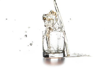 Whiskey pouring into glass with ice on light background..