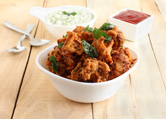 Pakoda, a traditional, popular, delicious, and an Indian vegetarian home-cooked snack, is made from deep-frying portions of split chickpea flour batter, in a bowl.