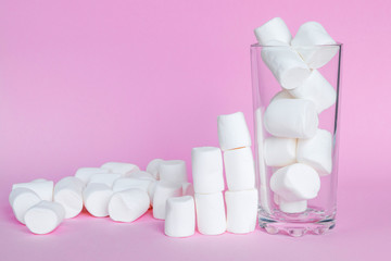 White marshmallows in the glass on pink background