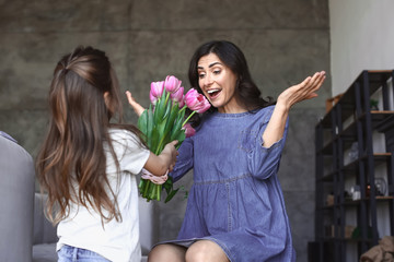 Cute little daughter greeting her mother at home