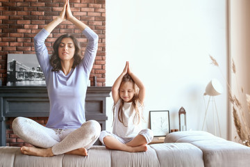 Mother with little daughter meditating at home