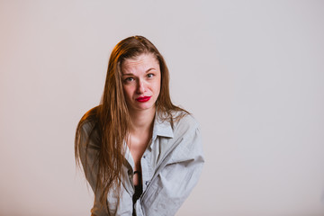 Sad young blonde girl with red lips on a gray background. Human emotion facial expression body...