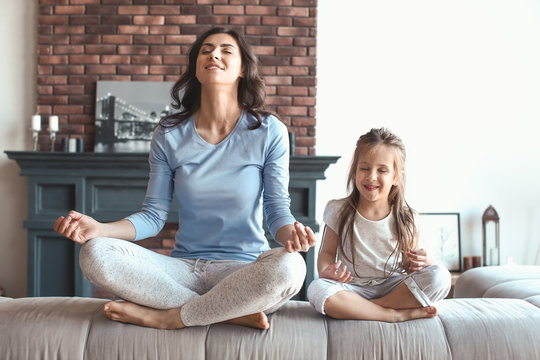 Mother with little daughter meditating at home - Powered by Adobe