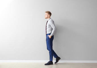 Fashionable young man near grey wall