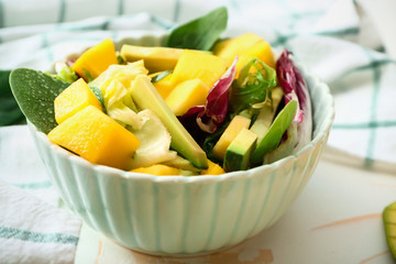 Bowl with tasty mango salad on table