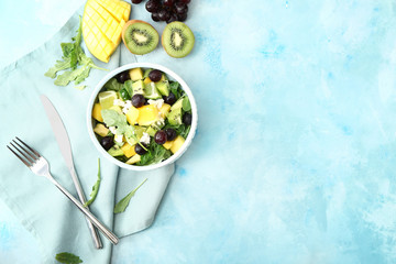 Bowl with tasty mango salad on color background