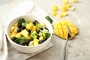 Bowl with tasty mango salad on table