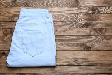 Stylish jeans pants on wooden background