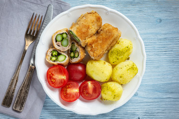 Roasted asparagus stuffed pork tenderloin served with potatoes and tomatoes.