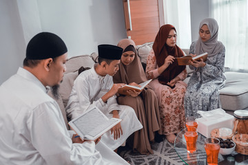 portrait of muslim family reading quran together in livingroom