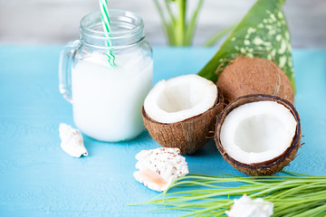 Coconut fruit whole and half, coconut milk on blue background