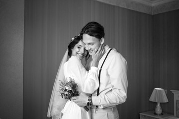 Meeting the bride and groom in the bedroom, the newlyweds are happy. Man with flowers in his hand.