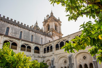 Obraz premium Low-angle shot of the Alcobaca Monastery from the cloister garden. Natural framing photography through the trees.