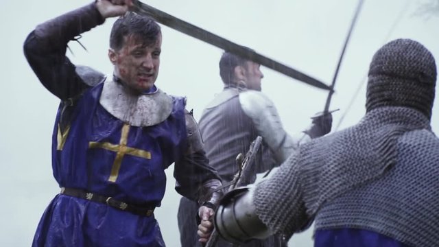 Warriors with blood and dirt on their faces are having a sword fight