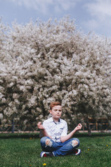 A boy outside in spring in front of the cherry in blossom having fun and enjoying smell of flowering spring garden