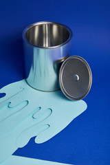 silver shiny can and dripping paper cut paint on bright blue background