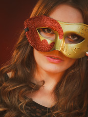 Closeup woman face with carnival golden red mask on dark