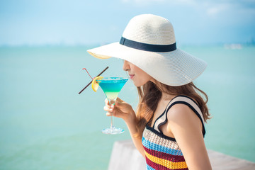 Beautiful woman is drinking ice summer drink in the beach, summer concept