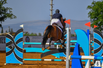 Young rider jumping over the obstacles during the horse jumping competition