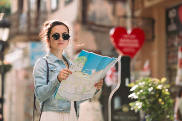 beautiful caucasian tourist woman looking at the map on the street of city