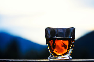 shot of whiskey at sunset dramatic sky on mountain landscape background