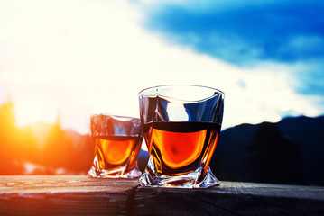 shot of whiskey at sunset dramatic sky on mountain landscape background