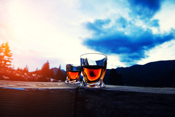 shot of whiskey at sunset dramatic sky on mountain landscape background