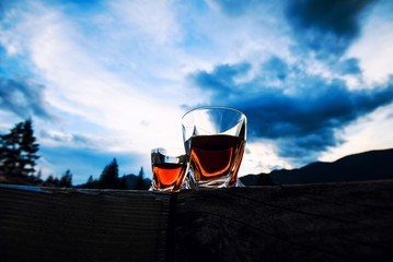 shot of whiskey at sunset dramatic sky on mountain landscape background